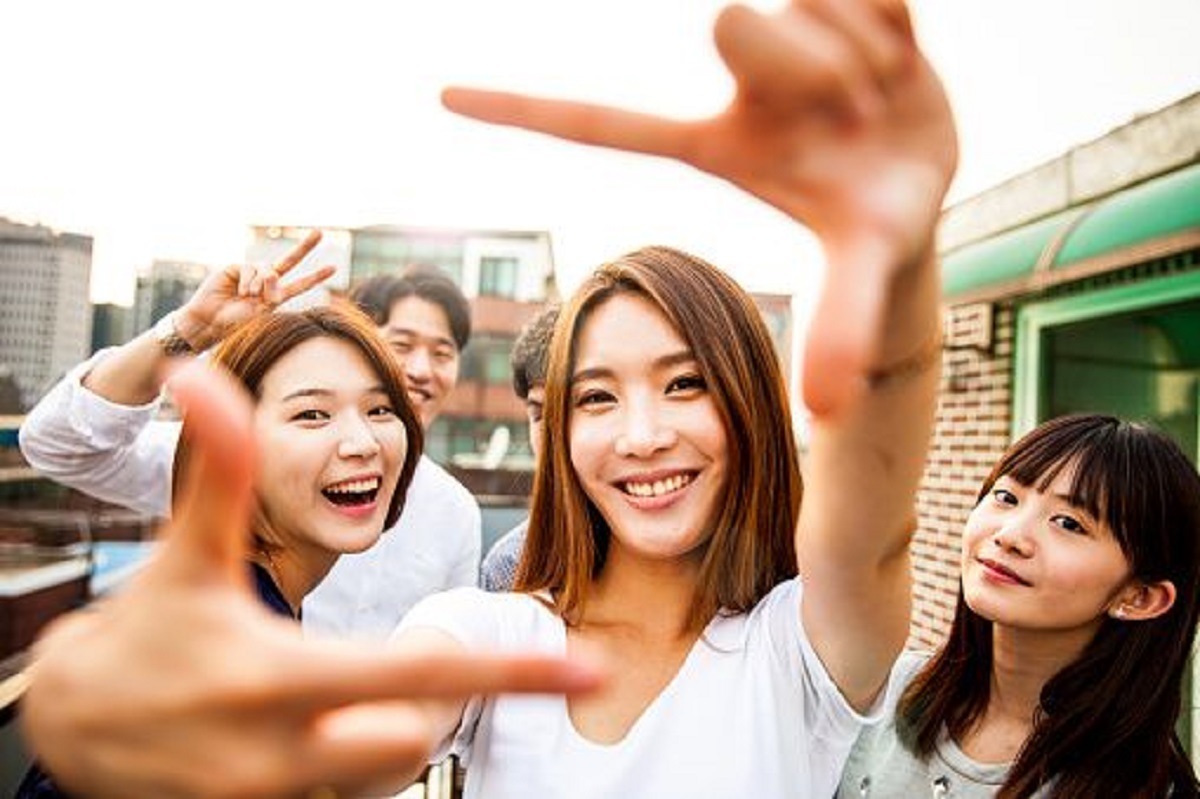 La imagen muestra jóvenes sonrientes mirando a cámara de rasgos coreanos