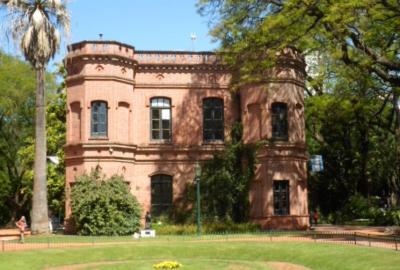 La imagen muestra una foto del Jardín Botánico donde se ve un jardín y un edificio diseñados por Carlos Thays
