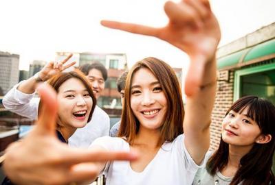 La imagen muestra jóvenes sonrientes mirando a cámara de rasgos coreanos