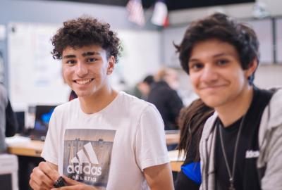 La imagen muestra a dos estudiantes jóvenes sonriendo y mirando a cámara