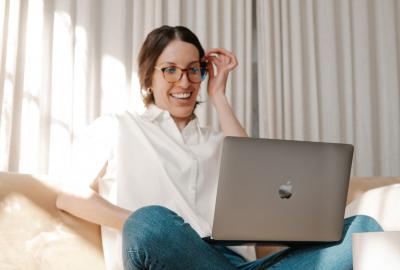 mujer en sillón mirando computadora sonriendo