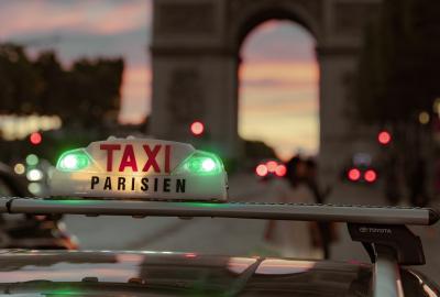 En la foto se ve un taxi de Paris yendo hacia el arco del triunfo 