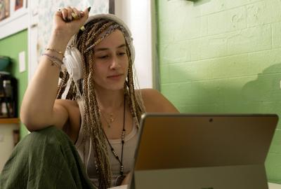 La imagen muestra a una muchacha joven frente a una computadora