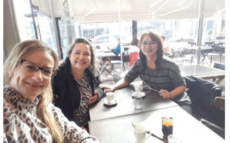 La imagen muestra a las profesoras mencionadas en el artículo sentadas frente a la mesa de un bar