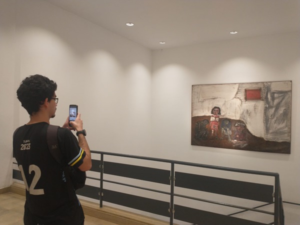 La imagen muestra a un estudiando tomando una foto a un cuadro en el Museo Nacionald de Bellas Artes