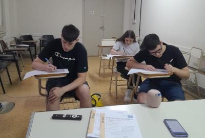 La imagen muestra a los estudianttes realizando el examen escrito
