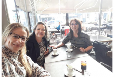 La imagen muestra a las profesoras mencionadas en el artículo sentadas frente a la mesa de un bar