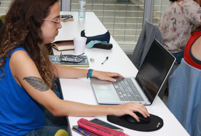 La imagen muestra a una estudiante frente a una computadora