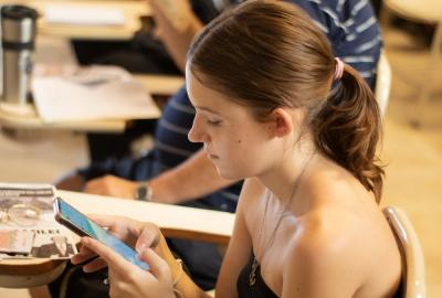 La imagen muestra a una estudiante mirando el celular