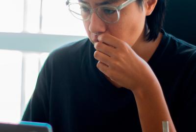 La imagen muestra a un estudiante frente a una computadora