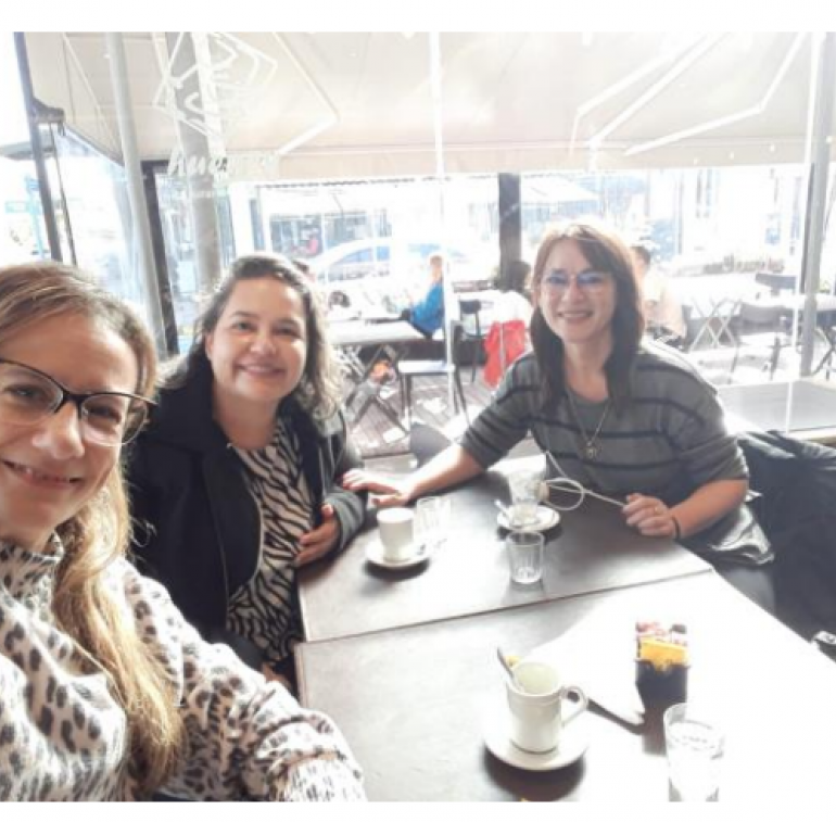 La imagen muestra a las profesoras mencionadas en el artículo sentadas frente a la mesa de un bar
